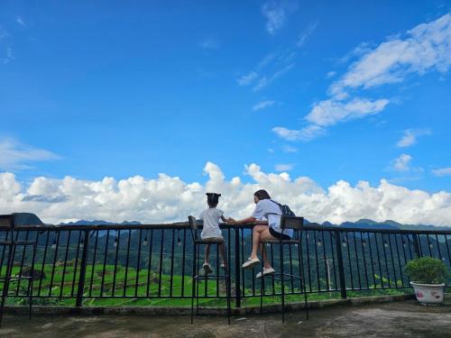 two people sitting on top of a fence at Pu Luong Serenity Lodge in Pu Luong