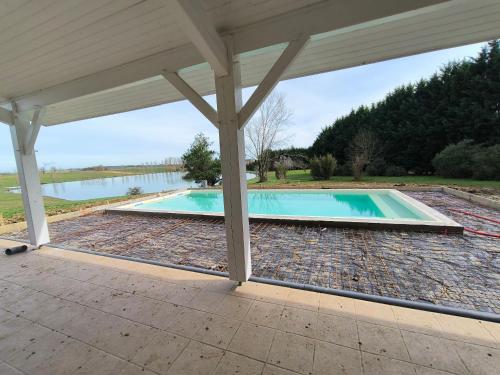 - une piscine sous une pergola avec une piscine dans l'établissement Villa Sheila - Au bord de l'eau avec piscine, à Préchac