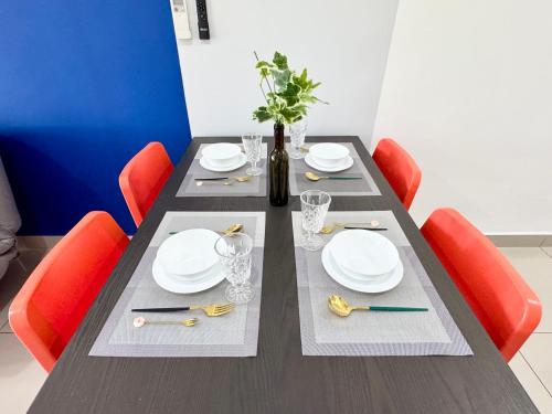 a dining room table with white plates and red chairs at Alinea Suites by Moka in Shah Alam