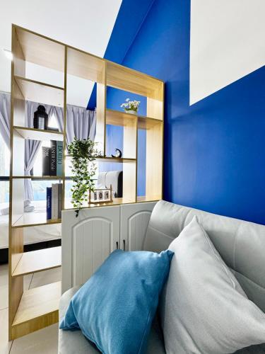 a living room with a couch and a blue wall at Alinea Suites by Moka in Shah Alam