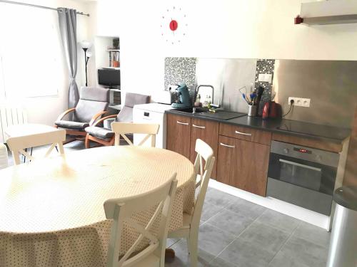 - une cuisine avec une table, une table et des chaises dans l'établissement Maison rénovée dans un corps de ferme, à Le Puy-Notre-Dame