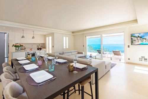 une salle à manger et un salon avec une table et des chaises dans l'établissement L Oasis Moderne piscine vue mer, à Roquebrune-Cap-Martin