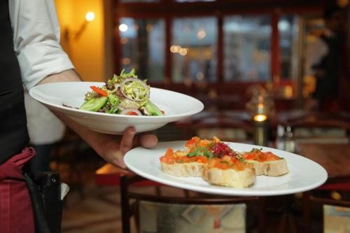 a person holding a plate with a salad and sandwich at Garner Hotel Berlin - Schöneberg by IHG in Berlin
