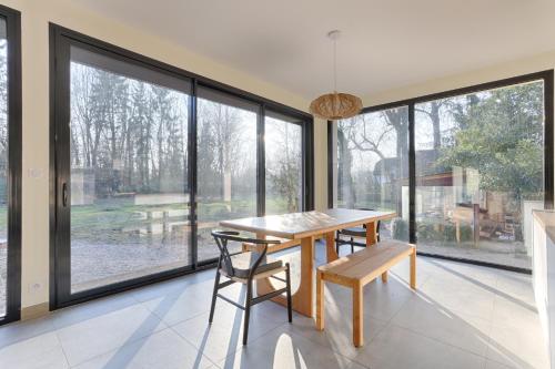 - une salle à manger avec une table, des chaises et de grandes fenêtres dans l'établissement Villa Nature à 10 Minutes de Disneyland Paris, à Chalifert