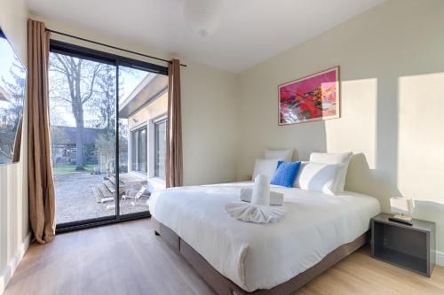 una camera da letto con un grande letto bianco e una grande finestra di Villa Nature à 10 Minutes de Disneyland Paris a Chalifert