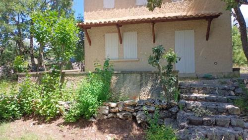 a small house with a stone wall in front of it at maison de 4000m2 in Monieux