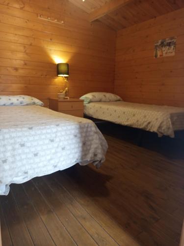 two beds in a room with wooden walls at Centro ecuestre Girasol in Chiclana de la Frontera