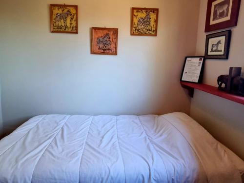 a white bed in a room with pictures on the wall at Pousterle de Sabran - Piscine & Hammam in Sabran