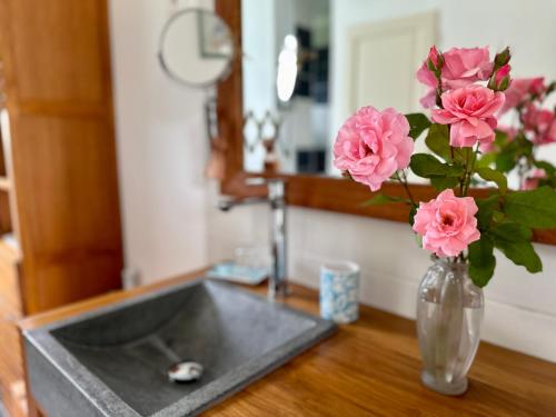 a vase with pink flowers sitting on a counter at Le Clos Beldane in Le Tâtre