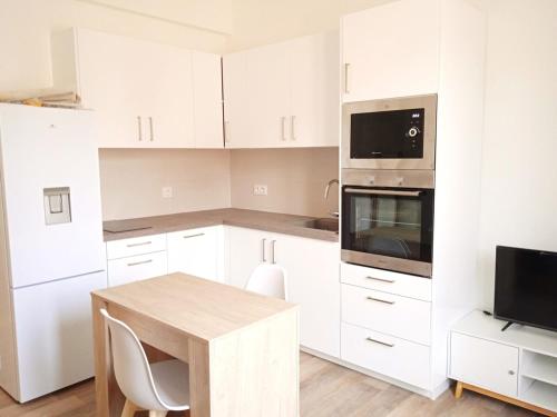 une cuisine avec des armoires blanches et une table en bois dans l'établissement 2pièces - 1 chambre - Port de Nice - balcon, à Nice