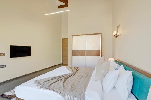 a bedroom with a white bed and a tv at ELIVAAS Villa 39 - Serene 6 BHK Retreat with Pvt Pool, Gaming Zone & Balcony in Lonavala