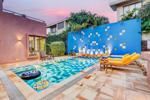 a house with a swimming pool with a blue wall at ELIVAAS Villa 39 - Serene 6 BHK Retreat with Pvt Pool, Gaming Zone & Balcony in Lonavala