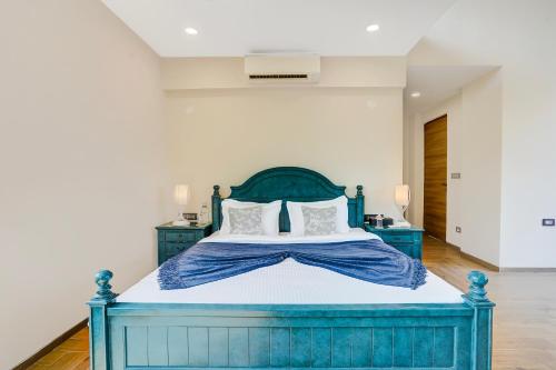 a bedroom with a blue bed with white pillows at ELIVAAS Villa 39 - Serene 6 BHK Retreat with Pvt Pool, Gaming Zone & Balcony in Lonavala