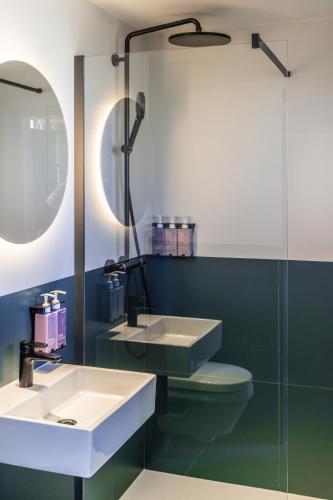 a bathroom with a sink and a toilet and a mirror at TRIBE Paris Clichy in Clichy