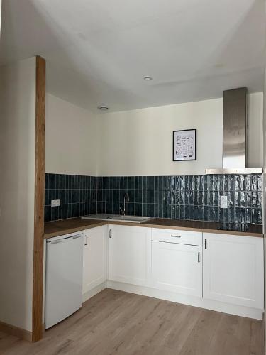 - une cuisine avec des placards blancs et du carrelage vert sur le mur dans l'établissement Cozy Appartment Champollion 1, à Figeac