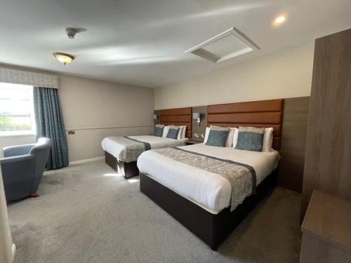 a hotel room with two beds and a chair at Bushtown Hotel & Spa in Coleraine