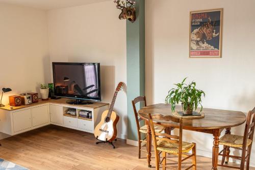 Cette chambre comprend une table, une guitare et une télévision. dans l'établissement T2 Écrin de ville, à Toulouse