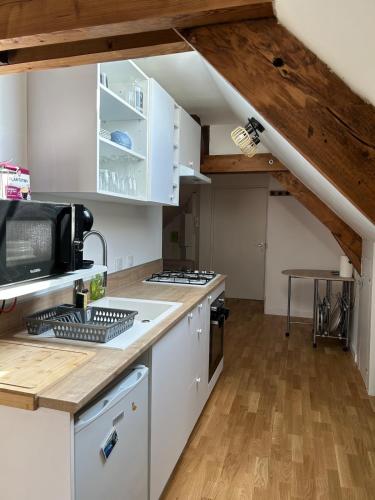 une cuisine avec des armoires blanches et un plancher en bois dans l'établissement Le Pomerol apartment, à Château-Gontier