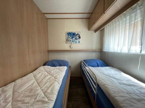two beds in a small room with a window at Veluwe Flirt in Epe