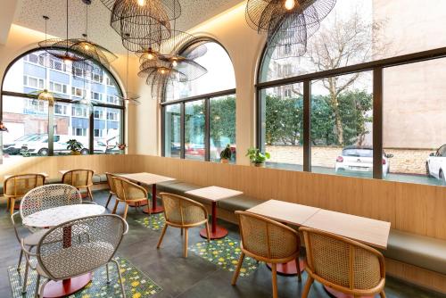 a restaurant with tables and chairs and windows at Ibis Styles Strasbourg Centre République in Strasbourg