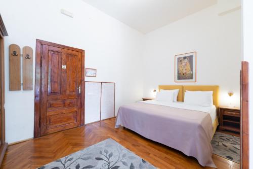 a bedroom with a white bed and a wooden door at Vila Camelia in Sinaia