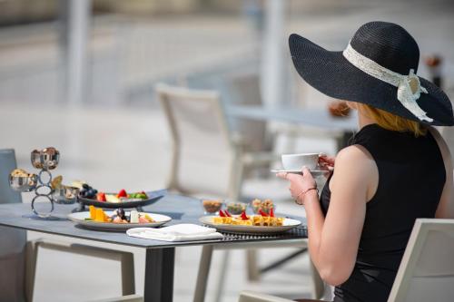 uma mulher de chapéu sentada à mesa com comida em Albatros Makadi Resort - 24 HRS All Inclusive em Hurghada