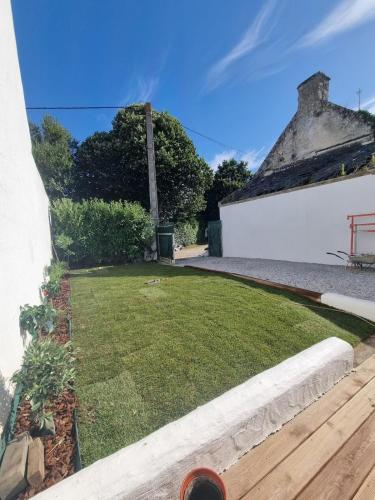 une cour avec une pelouse et un bâtiment dans l'établissement Maison de charme rénovée- Jardin - 5min des plages, à Arzon