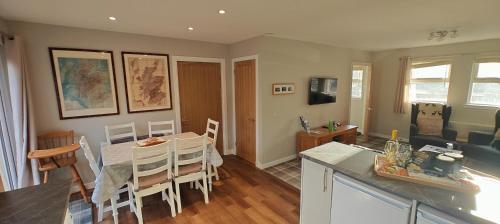 a kitchen and living room with a table and chairs at Ben Lomond Cottage in Arrochar