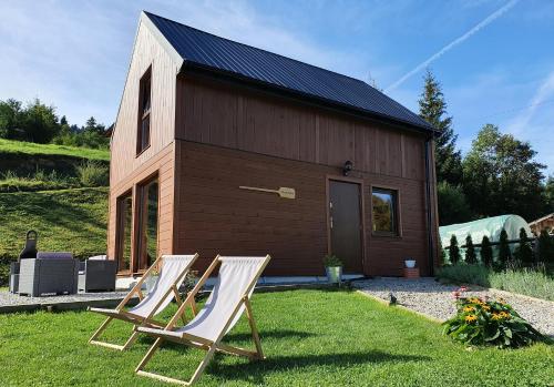 two lawn chairs in front of a tiny house at Młynówka Domek przy Młynie in Krościenko