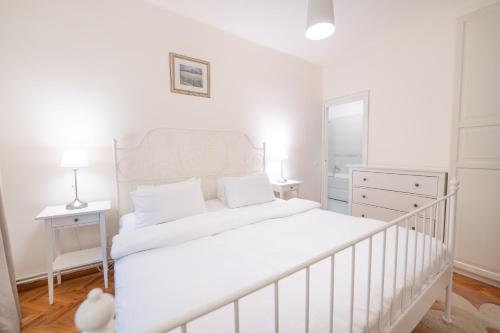a white bedroom with a white bed and a dresser at Vila Camelia in Sinaia