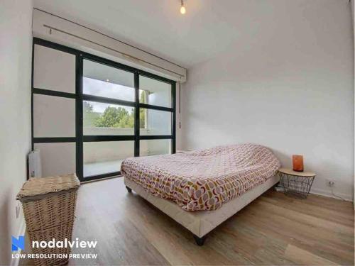 une chambre avec un lit et une grande fenêtre dans l'établissement Appartement au bord du lac, à Tours