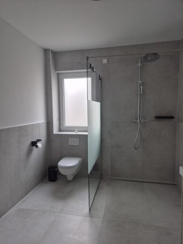 a bathroom with a shower and a toilet and a window at Luxsuite Still und Komfort 2 Balkon Elektrogrill Tischfussball TV-75 Zoll in Dinslaken