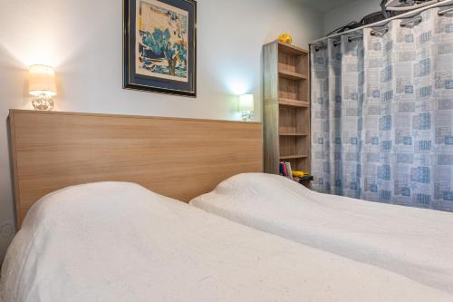 a bedroom with two white beds and a curtain at Le Rêve les Pieds dans l'eau in La Tranche-sur-Mer