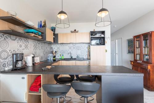 a kitchen with a large counter with stools at Le Rêve les Pieds dans l'eau in La Tranche-sur-Mer