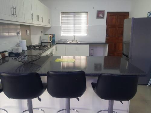 a kitchen with a counter with four black bar stools at Benmore Lodge in Ferrby