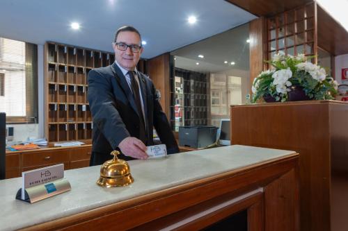 a man in a suit standing behind a counter at Hotel Barsotti in Brindisi