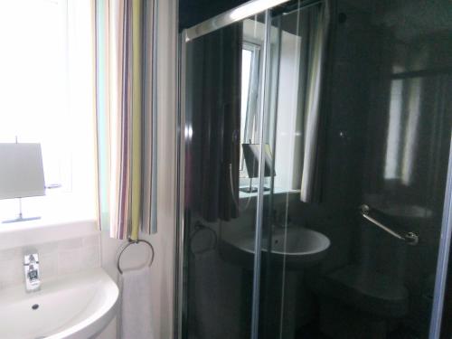 a bathroom with a glass shower and a sink at Crossroads Cottage in Sollas