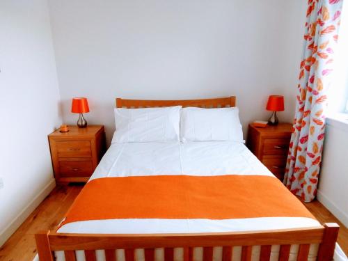 a bedroom with a bed with an orange blanket on it at Crossroads Cottage in Sollas