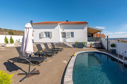 a house with a swimming pool with chairs and an umbrella at Villa Sea Pearl ZadarVillas in Maslenica