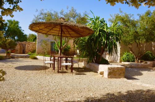 a table and chairs under an umbrella in a yard at Riad Pura Vida II in Essaouira