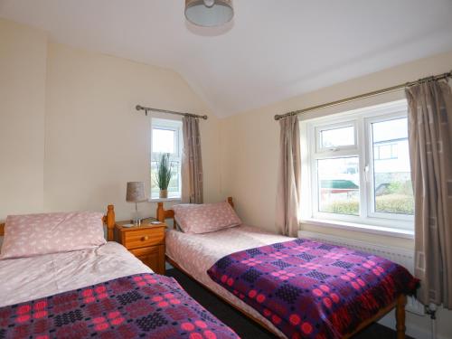 a bedroom with two beds and a window at Glan Y Don Bach in Abersoch