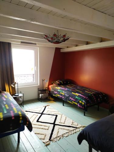 une chambre avec deux lits et un mur rouge dans l'établissement Atelier, à La Selle-sur-le-Bied