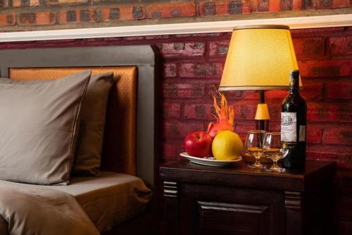 a table with a lamp and a bottle of wine and fruit at Cat Ba Spring Homestay in Cat Ba