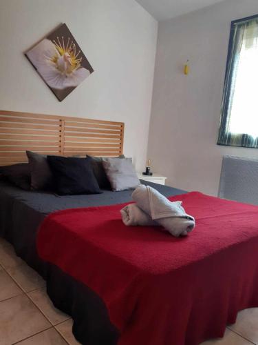 un chien dormant sur un lit avec une couverture rouge dans l'établissement Le Cap'tivant, au Cap d'Agde