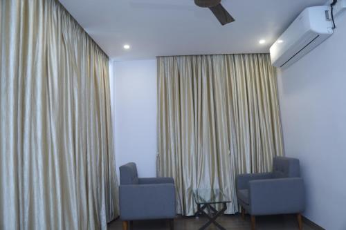 two chairs and a table in a room with curtains at Geetanjali International Annex a unit of Geetanjali International in Deoghar