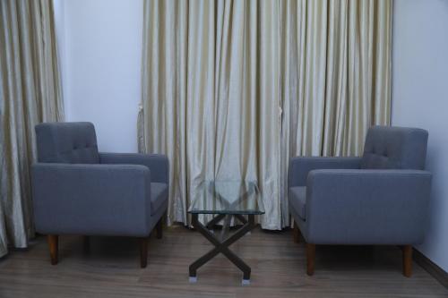 two chairs and a table in a room with curtains at Geetanjali International Annex a unit of Geetanjali International in Deoghar