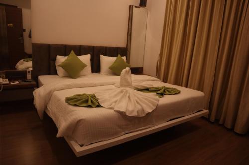 a bedroom with a bed with green towels on it at Geetanjali International Annex a unit of Geetanjali International in Deoghar