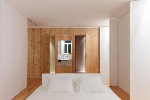 a bedroom with a white bed and wooden walls at samesame living in Lisbon