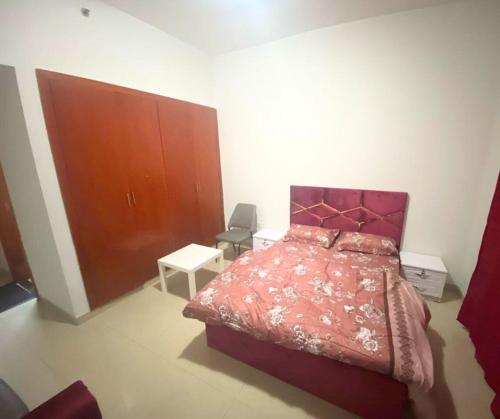 a bedroom with a red bed and a wooden cabinet at ASDK Home 908-14 in Dubai