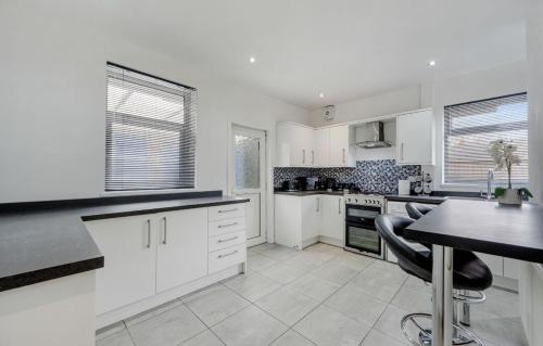 a kitchen with white cabinets and a table and chairs at Comfortable Cottage in Greater Manchester in Glazebury